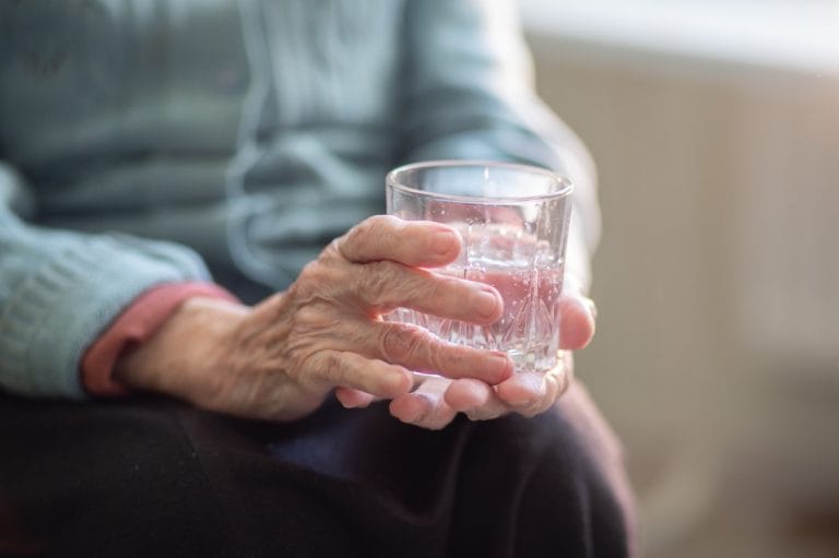 Elderly ladies hand with glass of water